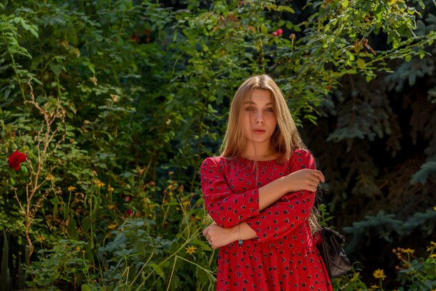 Uma garota em um vestido vermelho com cabelo comprido em um fundo de vegetação no verão. linda garota na natureza