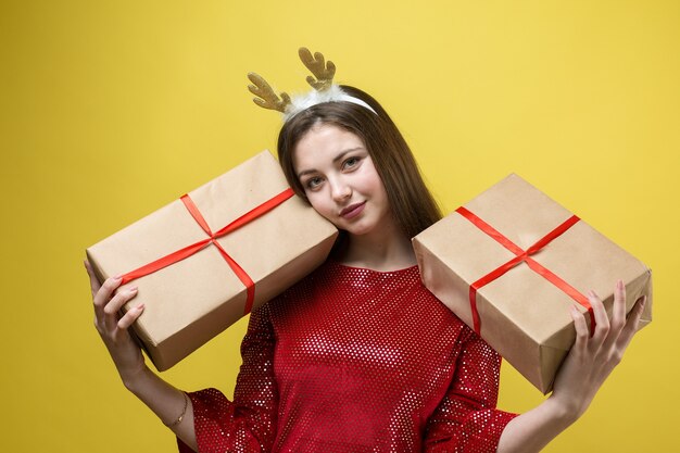 Uma garota em um vestido vermelho com presentes em um fundo amarelo.