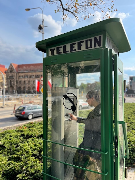 Uma garota em uma cabine telefônica moderna na praça da cidade