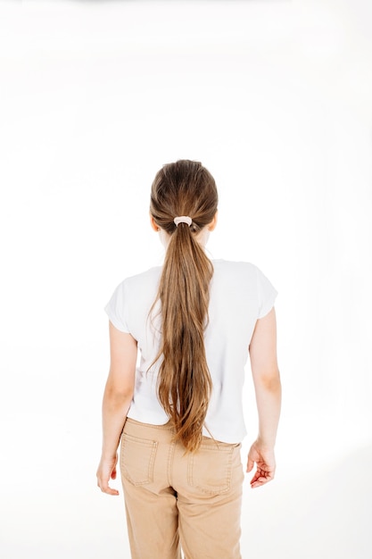 Foto uma garota em uma camiseta branca, calças com cabelo comprido em um fundo branco, estúdio, adolescente