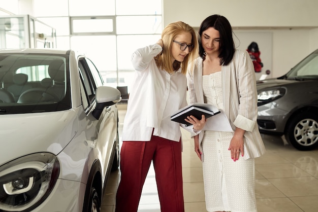 Uma garota em uma concessionária de automóveis compra um pequeno carro urbano.