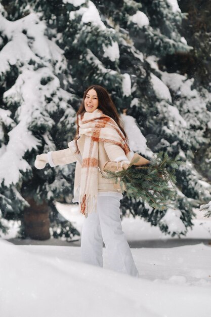 Uma garota em uma floresta de inverno com um buquê de ramos de abeto Inverno nevado