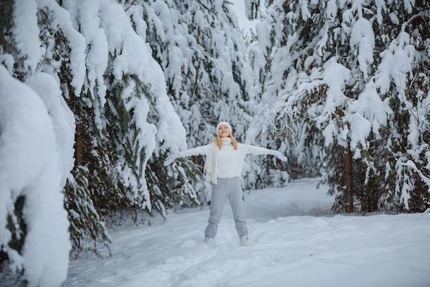 Uma garota em uma floresta de inverno, loira, um passeio divertido na natureza