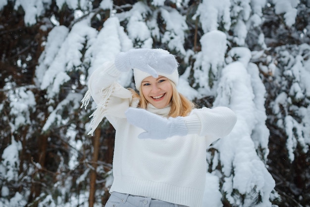 Uma garota em uma floresta de inverno, loira, um passeio divertido na natureza