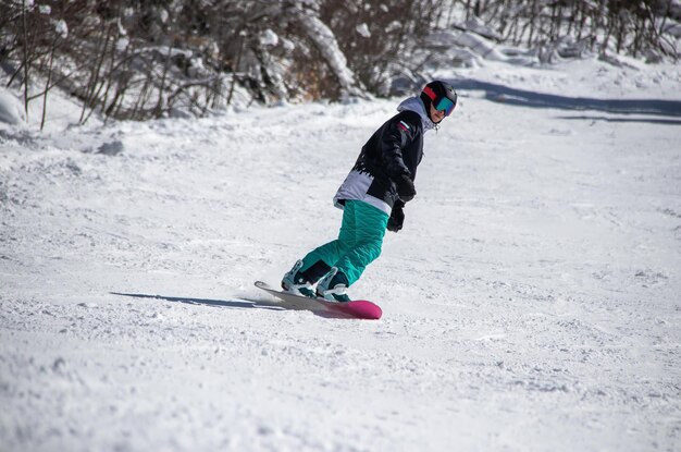 Uma garota em uma prancha de snowboard desce a encosta da montanha