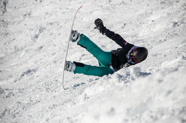 Uma garota em uma prancha de snowboard desce a encosta da montanha