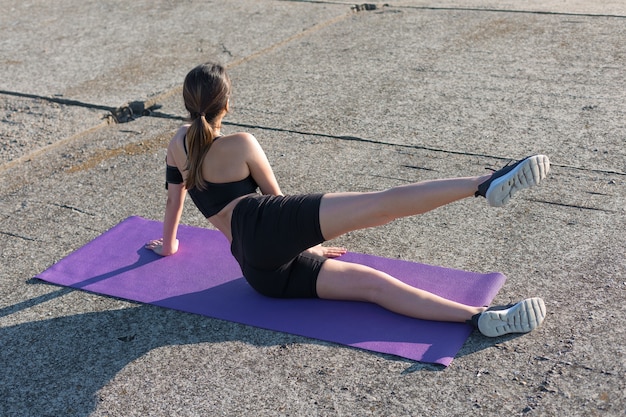 Uma garota esportiva esguia em leggings e um top descansando entre os exercícios.