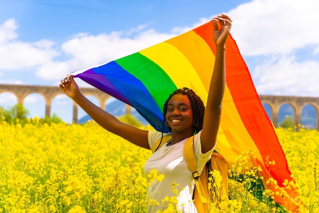 Uma garota étnica negra com tranças segurando a bandeira lgbt