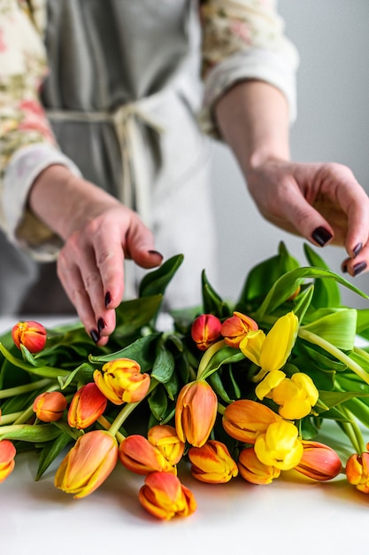 Uma garota faz um buquê de tulipas amarelas, laranja e vermelhas