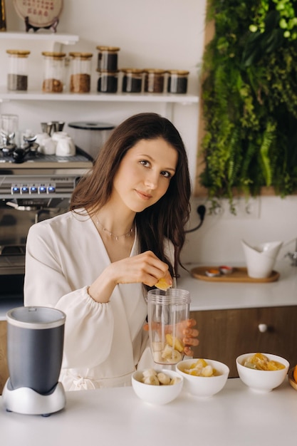 Uma garota faz um coquetel de desintoxicação de frutas na cozinha Dieta para perda de peso