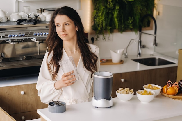 Uma garota faz um coquetel de desintoxicação de frutas na cozinha Dieta para perda de peso