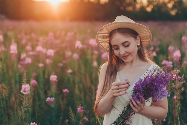 uma garota feliz com buquê caminha por um prado de flores. Amor e primavera florescendo