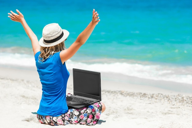 Uma garota feliz com laptop perto da viagem de fim de semana à beira-mar