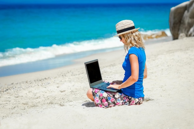 Uma garota feliz com laptop perto da viagem de fim de semana à beira-mar