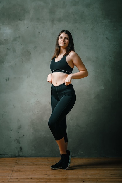 Uma garota forte e bonita de esportes fitness em roupas esportivas posando