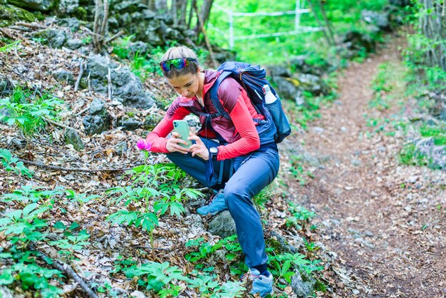 Uma garota fotografa flores com um smartphone durante uma viagem na colina