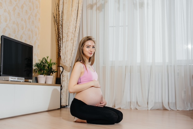 Uma garota grávida faz yoga em casa. Saúde