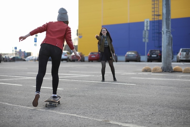 Uma garota jovem hippie está andando de skate. Namoradas de garotas para um passeio na cidade com um skate. Esportes de primavera na rua com um skate.