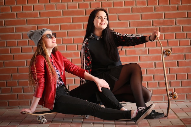 Uma garota jovem hippie está andando de skate. namoradas garotas para um passeio na cidade com um skate. esportes de primavera na rua com um skate.