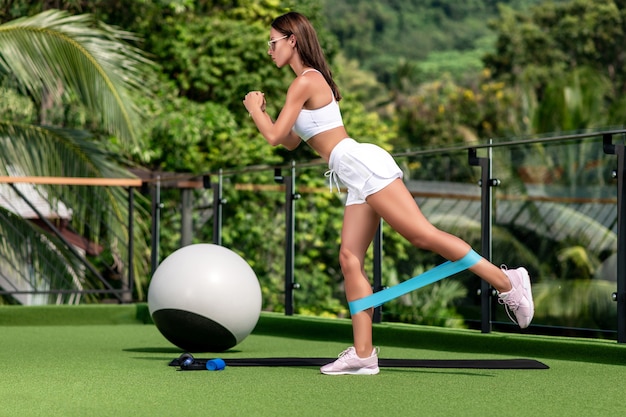 Uma garota linda e esguia posa com um uniforme esportivo com elásticos para esportes nas pernas