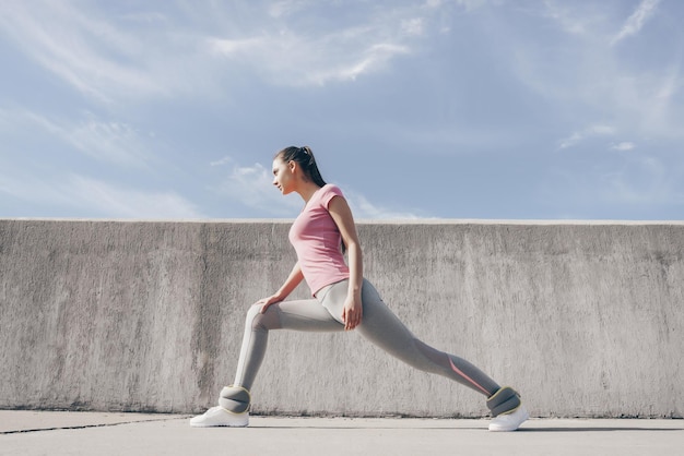 Uma garota magra desportiva amassa e estica antes de um exercício ao ar livre