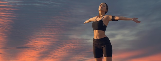 Uma garota magra esportiva em leggings e um top está de pé com um tapete de treinamento descansando entre exercícios lindas nuvens dramáticas atmosféricas