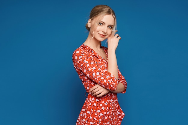 Uma garota modelo em um vestido de verão colorido posando sobre fundo azul isolado jovem mulher caucasiana ...