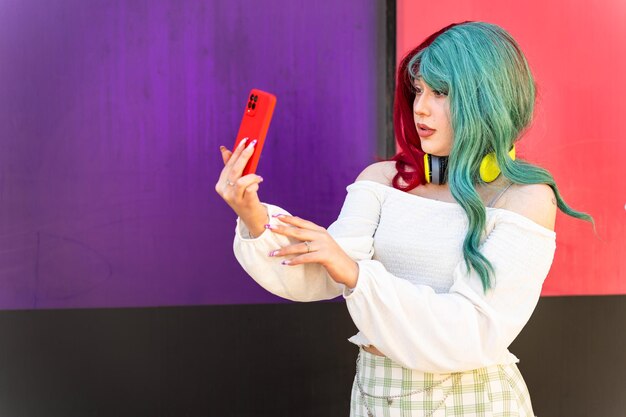 Uma garota moderna com cabelos vermelhos e verdes tirando uma foto com seu telefone
