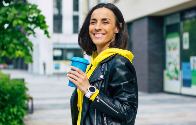 Uma garota moderna em uma caminhada! jovem garota moderna, curtindo o dia, com uma bebida quente em sua confortável caneca térmica, com seu novo e bonito smartwatch.