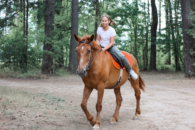 Uma garota monta um cavalo no verão quente na floresta