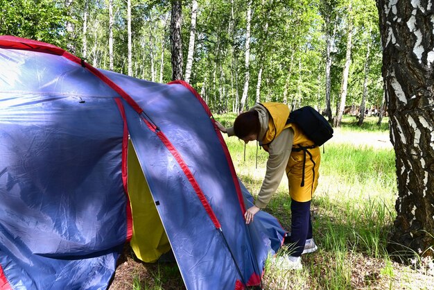 Uma garota monta uma barraca de acampamento durante sua estadia na natureza