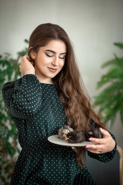 Uma garota na Páscoa com galinhas está sentada à mesa