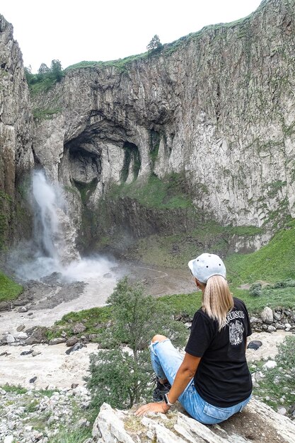 Uma garota no fundo da cachoeira TuzlukShapa no território de KabardinoBalkaria Caucasus Rússia