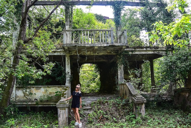 Uma garota no fundo de uma pitoresca casa abandonada na vegetação Nova Athos Abkhazia 2019