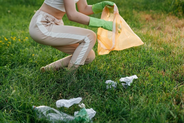 Uma garota no parque ao pôr do sol está envolvida na coleta de lixo no parque Reciclagem de resíduos de cuidados ambientais Separando lixo