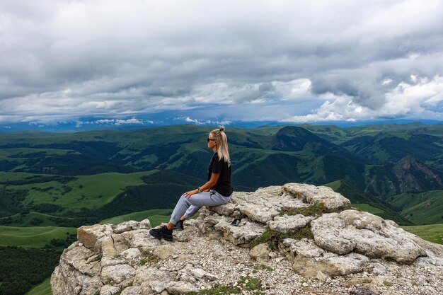 Uma garota no penhasco do planalto no contexto do Monte Elbrus Bermamyt