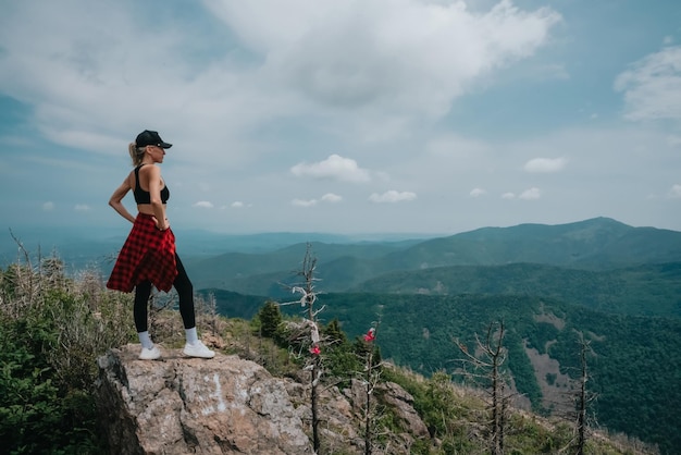 Uma garota no topo da montanha Falaza olha para um belo vale montanhoso Viagem e turismo Caminhadas