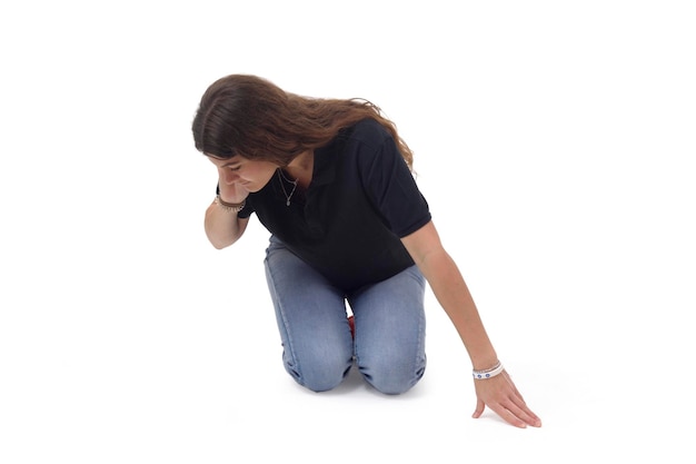 Foto uma garota que está de joelhos no chão procurando algo ao lado em um fundo branco