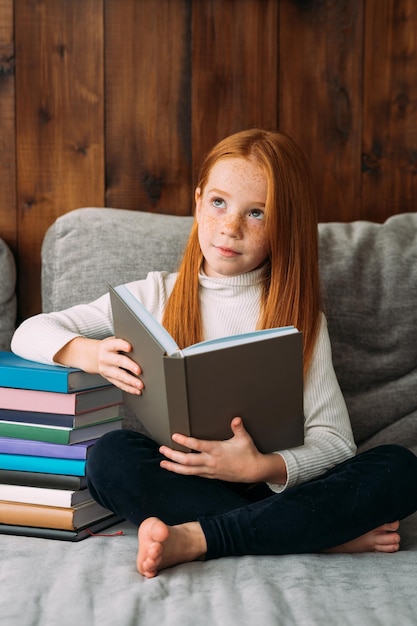 Uma garota ruiva com um livro nas mãos senta-se na posição de lótus e lê