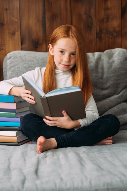 Uma garota ruiva com um livro nas mãos senta-se na posição de lótus e lê