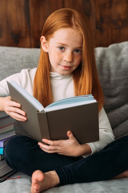 Uma garota ruiva com um livro nas mãos senta-se na posição de lótus e lê