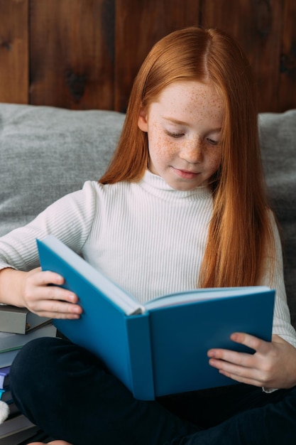 Uma garota ruiva com um livro nas mãos senta-se na posição de lótus e lê