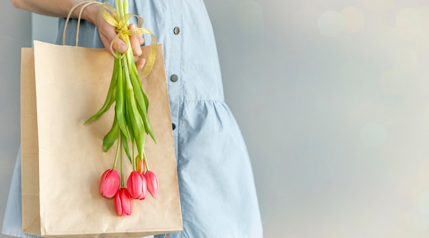 Uma garota segura um buquê de flores em um saco de papel marrom como presente para o dia dos pais Fundo do dia das mães com lugar para texto eu te amo conceito Valorize as tradições familiares