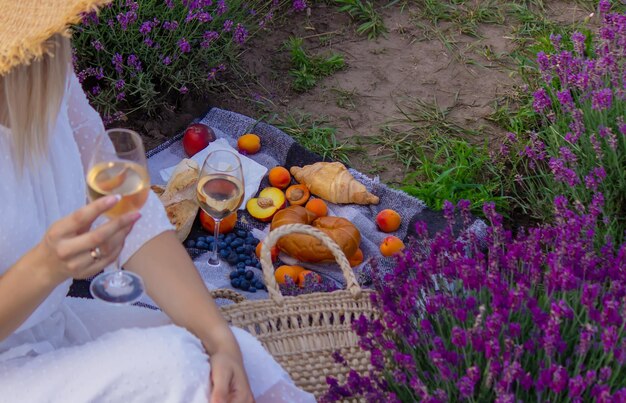 Uma garota segura um copo de vinho branco contra o pano de fundo de um campo de lavanda Uma garota bebe vinho em um campo de lavanda