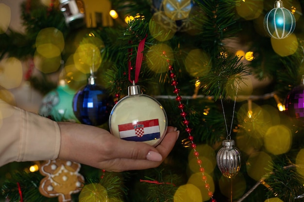 Uma garota segura uma decoração em uma árvore de Natal com a bandeira da Croácia