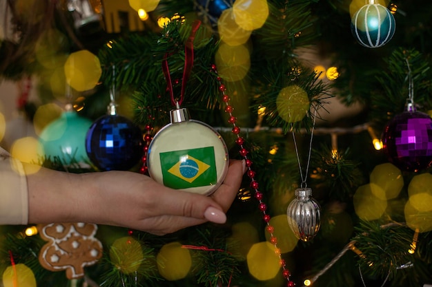 Foto uma garota segura uma decoração em uma árvore de natal com a bandeira do brasil