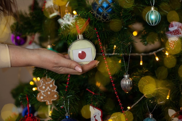 Uma garota segura uma decoração em uma árvore de Natal com a bandeira do Japão