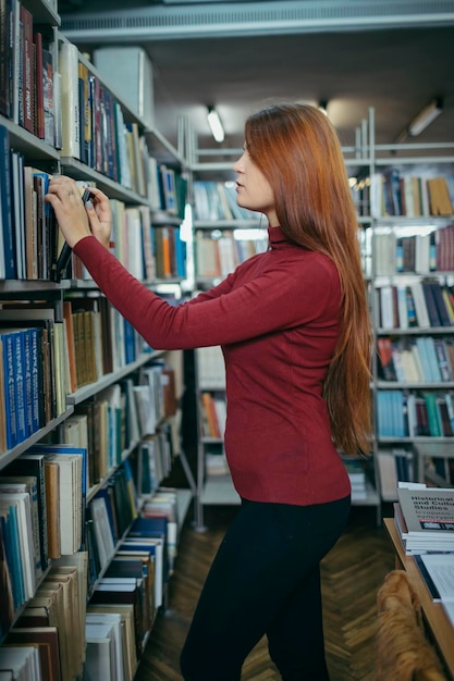 Uma garota segurando um estudante de estante de livros na biblioteca