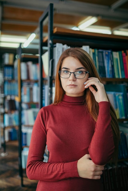 Uma garota segurando uma estante de livros Foto de alta qualidade Aluno na biblioteca