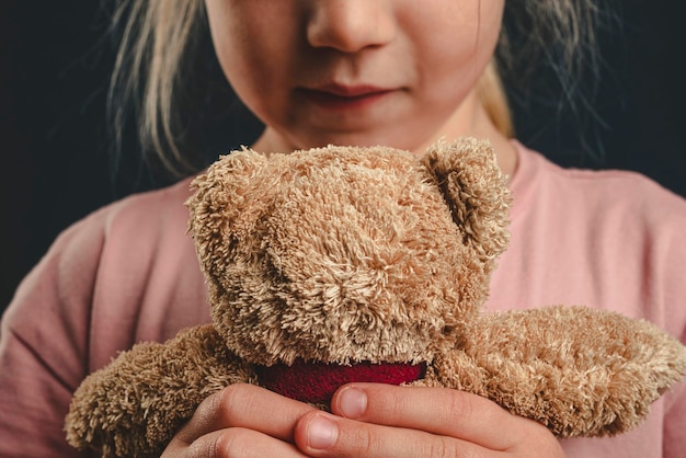 Uma garota solitária abraça um ursinho de pelúcia briga na família a criança está com medo do divórcio dos pais
